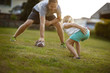 © Erickson Stock - Mid adult man playing American football with his daughter on a lawn.