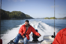 Mature Man Steering A Motor At The Rear Of A Boat.