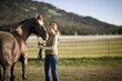 © Erickson Stock - Young adult girl standing with a horse in a field.