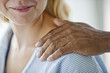 © Erickson Stock - Female hospital patient smiling as she looks at the comforting hand laid on her shoulder.