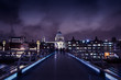 Millennium Bridge and St Paul's Cathedral on London skyline at night with dark cloudy moody sky