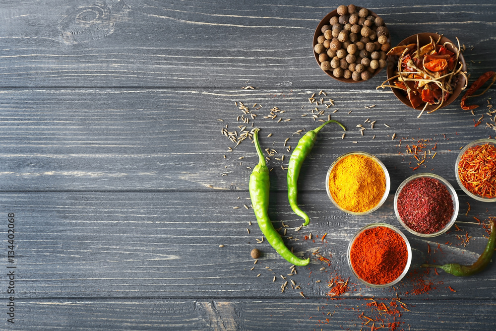 Aromatic spices in glass bowls on blue wooden background
