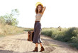 © Africa Studio - Beautiful young woman with suitcase standing on countryside road