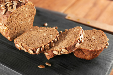 Wall Mural - Sliced rye bread with seeds on wooden cutting board closeup