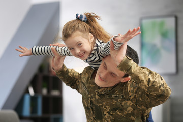 Poster - Soldier in camouflage playing with his daughter at home