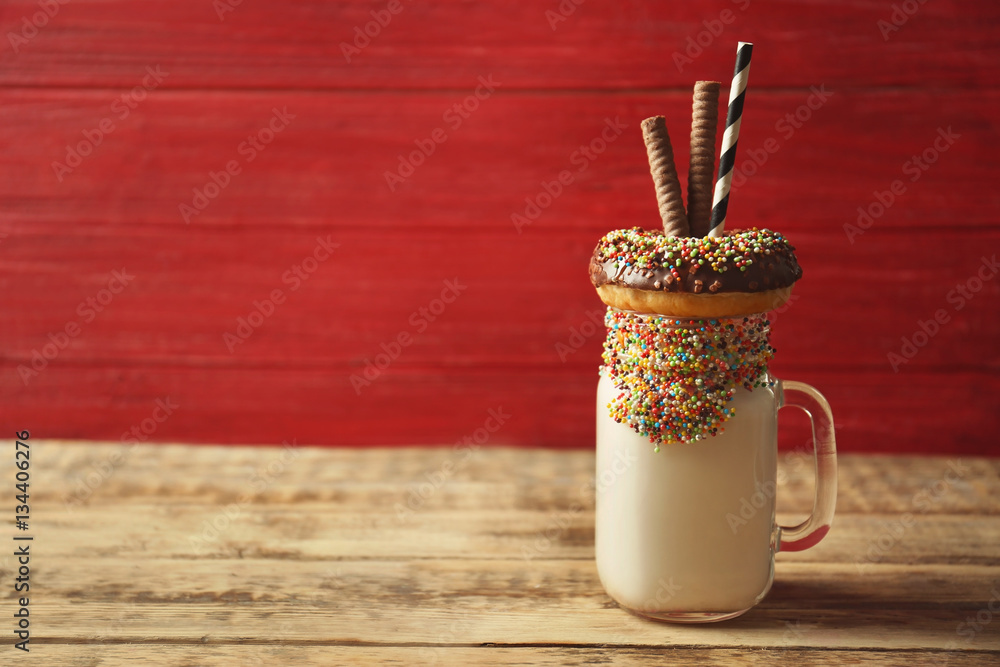 Milkshake, donut and other sweets in jar on wooden background