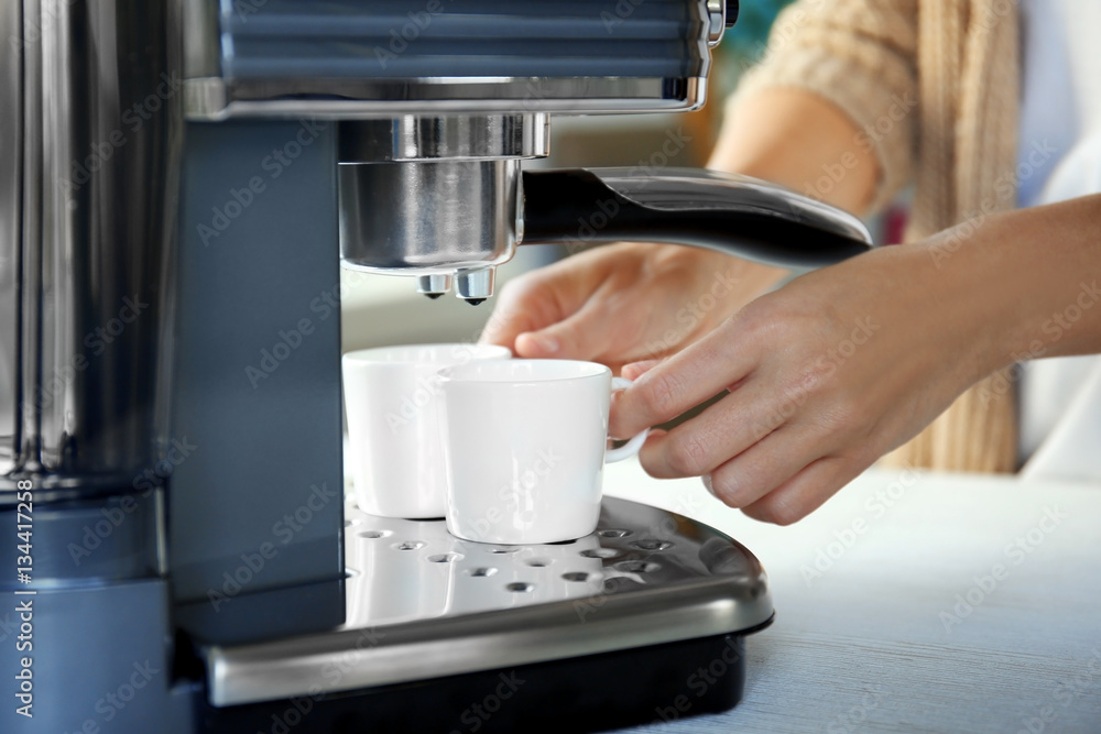 Woman making aromatic espresso in coffee machine, closeup