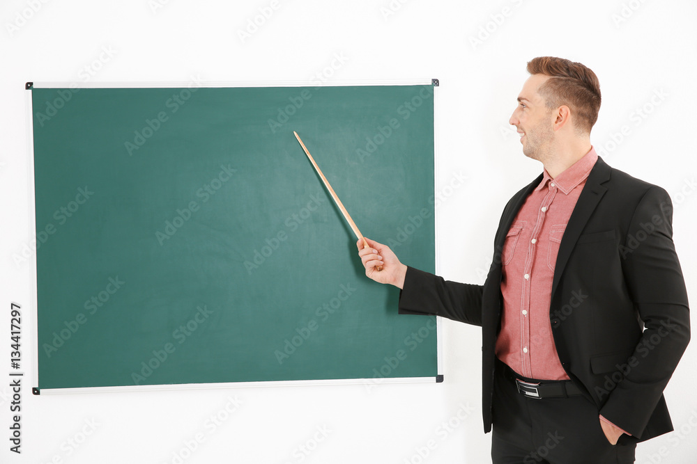 Young male teacher beside blackboard on white blackboard