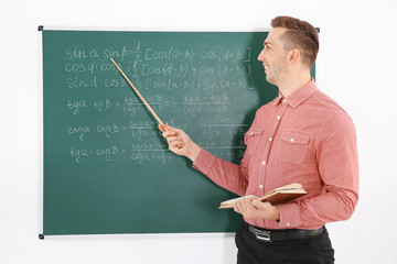 Wall Mural - Young male teacher beside blackboard on white blackboard