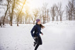 © sushytska - Runner jogging in snow. Young woman fitness model running in a city park