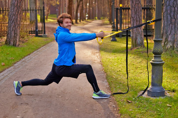 Wall Mural - A man exercising in a park with trx fitness strips.