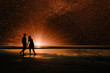 Silhouettes of loving couple, walking along the beach and imagine in the sky, the universe, stars and planets. People are on another planet. Elements of this Image Furnished by NASA  