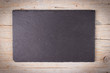 Rectangular plate made of black slate on wooden background.