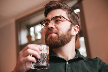 Handsome bearded man drinking whiskey.