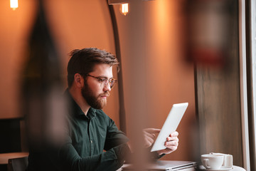 Sticker - Attractive bearded young man using tablet computer.