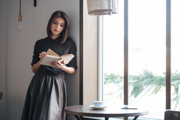 Young beautiful lady standing near window in cafe