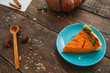 Piece of pumpkin pie on wooden table. Traditional american autumn dessert served with spoon, free space. Homemade bakery, seasonal food, kitchen concept