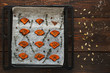 Baked pumpkin tray on table with seeds flat lay. Top view on wooden kitchen background with prepared spiced squash slices. Seasonal menu, healthy food, vegetarian menu concept