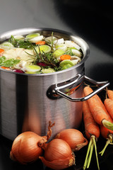 Broth with carrots, onions various fresh vegetables in a pot - c