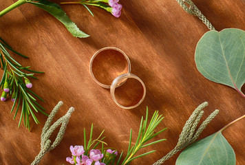 Wall Mural - Closeup of wedding rings and flowers on wooden background