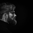 Black and white close up image of serious brutal bearded man on