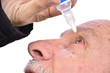 Senior man dripping a red eye with eye drops