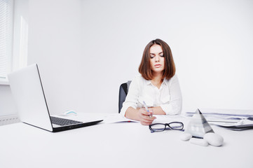 Portrait of beautiful young office woman working with paper at office desk