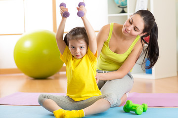 family mother and child daughter are engaged in fitness, yoga, exercise at home or sport hall