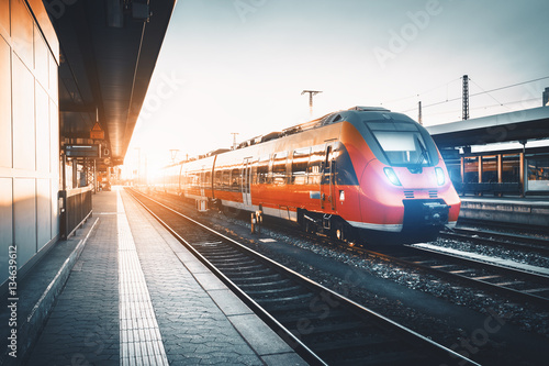 Cuadros en Lienzo Moderno tren de cercanías rojo de alta velocidad en el ferrocarril al atardecer