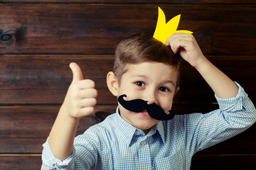 A kid with props for a photo booth gives a thumbs-up.. The child