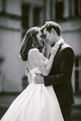 Wall Mural - Groom holds cheerful bride in his tender embraces posing before