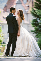 Wall Mural - Bride in luxurious ivory dress looks over groom's shoulder while