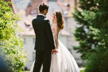 Wall Mural - Cheerful bride looks over groom's shoulder posing with him betwe