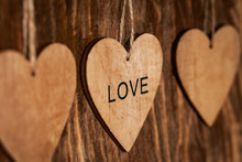 Wooden Brown Heart With Inscription: "LOVE" On Wooden Background Close Up.