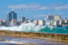 The Havana Skyline With Waves Crashing On The Malecon Seawall