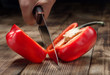© kucherav - Man's hand with big kitchen knife cuts red pepper