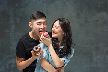 Young asian couple enjoy eating of sweet colorful donut