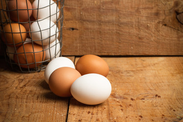 Huevos blancos y colorados de gallina sobre mesa de madera rústica. Vista de frente y de cerca. Copy space