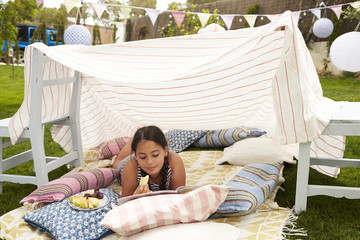 Wall Mural - Girl Reading Book and Eating Snack In Home Made Garden Den