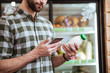 © Drobot Dean - Man with bottle of milk using smartphone at grocery shop