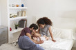 © Monkey Business - Parents Playing With Baby Daughter In Bedroom At Home