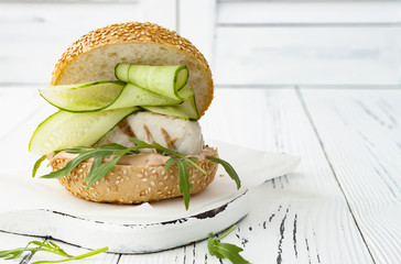 Wall Mural - Homemade crispy spring fish burger with spicy chilli mayo on white rustic wooden board over light background. Copy space