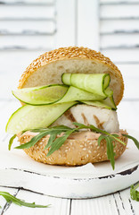 Wall Mural - Homemade crispy spring fish burger with spicy chilli mayo on white rustic wooden board over light background. Copy space