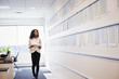 © Mint Images - A woman standing in an office looking at a display holding pieces of paper.