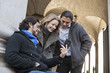 © Mint Images - Three people, two men and a woman looking at the screen of a smart phone.