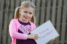 Adorable School Age Girl Wearing Pink And Holding Sign Saying Future President For Women's Rights Issues