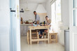 © Monkey Business - Kids at kitchen table with mum, dad cooks, view from doorway