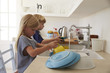 © Monkey Business - Brother and sister kneeling on chairs to wash up in kitchen