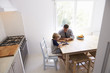 © Monkey Business - Dad and son use tablet in kitchen, elevated view from doorway