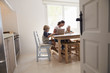 © Monkey Business - Mum and two kids working at kitchen table, seen from doorway